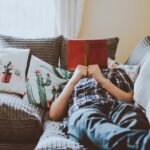 person-laying-on-sofa-while-reading-book-1471991