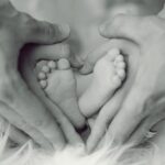 grayscale-photo-of-baby-feet-with-father-and-mother-hands-in-733881