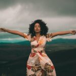 woman-in-white-and-red-floral-dress-standing-on-green-grass-3605015